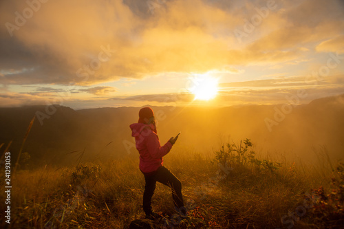 rear of happy woman stand on top mountain looking view with sunrise and mist at Doi Langka Luang, Chiang Rai province. soft focus.