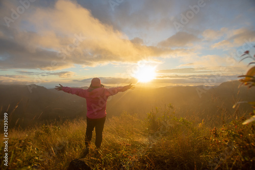 rear of happy woman stand on top mountain looking view with sunrise and mist at Doi Langka Luang, Chiang Rai province. soft focus.