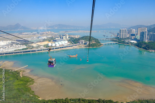 Photography Ngong Ping Cable car with tourists over harbor, mountains and city background, to visit the Tian Tan or the Big Buddha located at Po Lin Monastery in Lantau Island