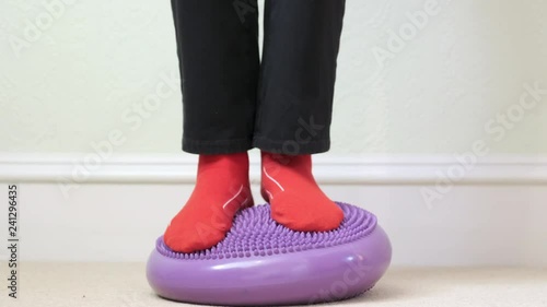 Balance board ankle exercise purple inflatable wobble feet close up red socks for rehabilitation of foot or knee joint injuries
