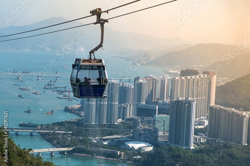 Ngong Ping Cable car with tourists over harbor, mountains and city background, to visit the Tian Tan or the Big Buddha located at Po Lin Monastery in Lantau Island. landmark and popular in Hong Kong