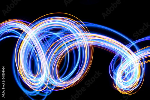 Light painting photography, blue and gold loops and swirls of vibrant color, long exposure photo of fairy lights against a black background photo