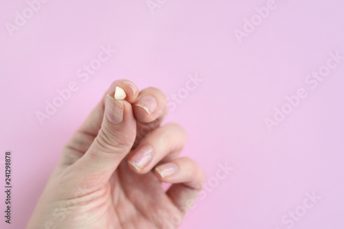 White woman palm holding first lost milk tooth on neutral pink background. Hand with little loose tooth. Kids dentistry. Miss children teeth in female fingers with selective focus.
