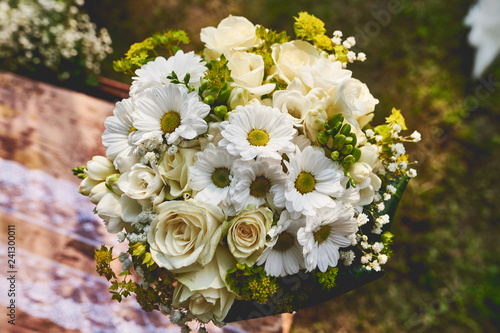 Rustic wedding bouquet made of roses and daisies decorated with white lace and sackcloth