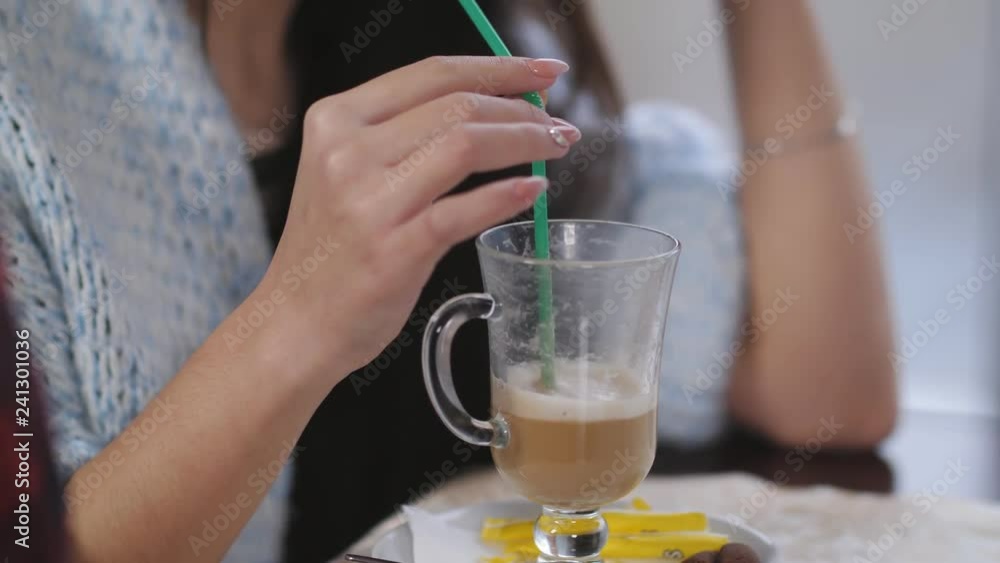 Young beautiful girl sitting in a cafe by the window, smiling and drinking latte Young beautiful girl sitting in a cafe by the window, smiling and drinking latte