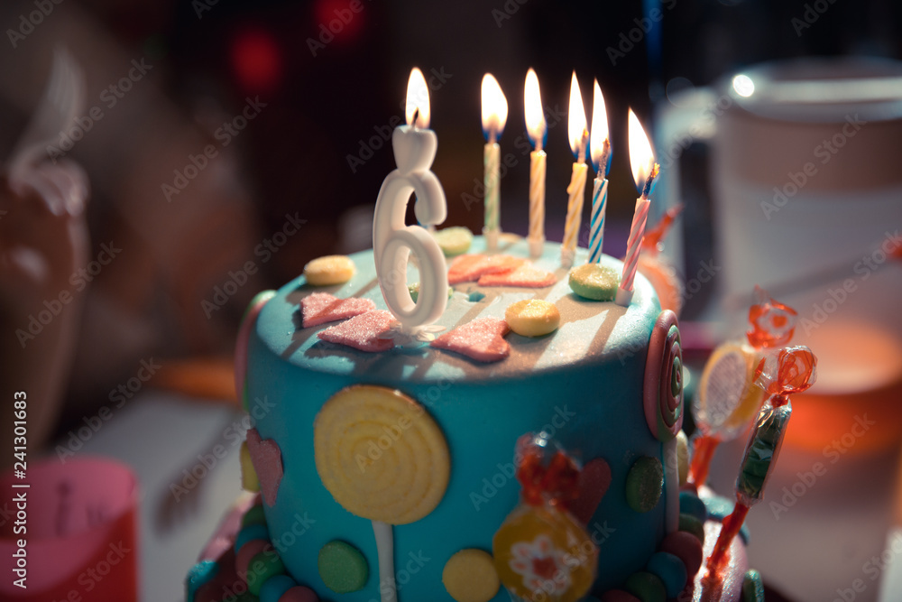 Birthday cake with burning candles and age 6 candle in the dark