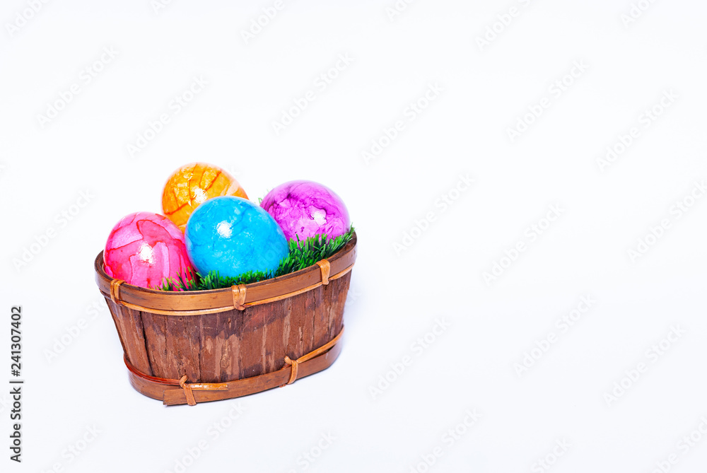 A basket filled with green grass and colorful easter eggs on white background with copy space A basket filled with green grass and colorful easter eggs on white background with copy space