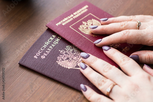 Travel, working, holiday, business concept. A woman holding a Russian passport on the wooden background. People is planning trip or vacation. Close up of woman's hands.
