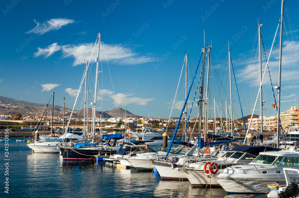 Panoramic view of boats and yachts at dockside on background of hilly shore and cloudy blue sky