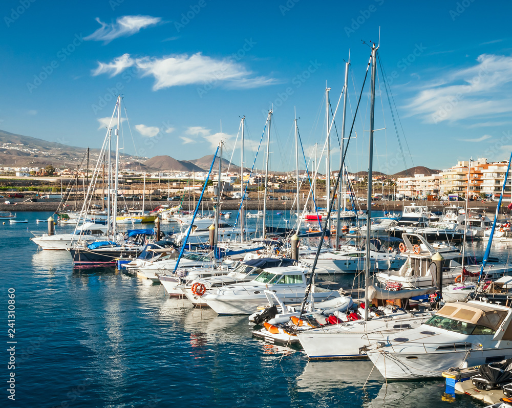 Panoramic view of boats and yachts at dockside on background of hilly shore and cloudy blue sky