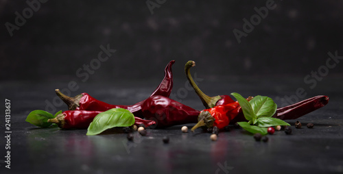 chili peppers with basil and peppercorns on a rustic surface