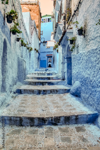 One of the many alleys of the Chaouen medina, (or Chefchaouen), adorned with pots hanging on the wall. Morocco, North Africa © juanorihuela