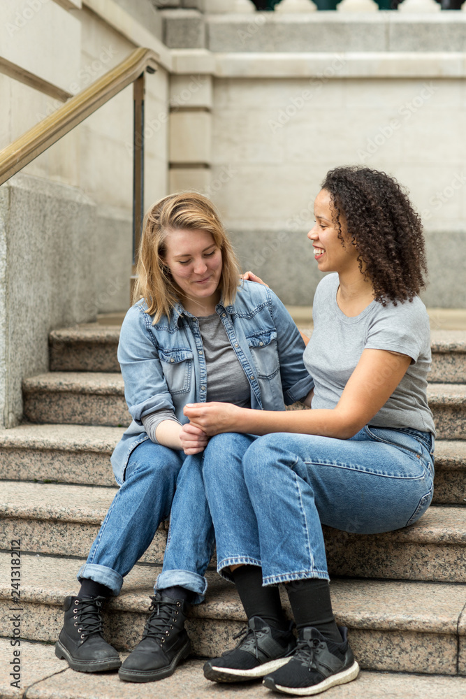 Happy lesbian couple sitting together talking Happy lesbian couple sitting together talking