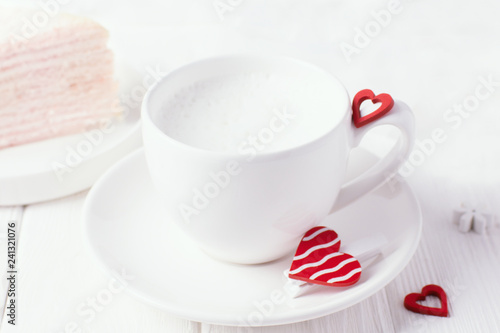 Coffee with milk foam and red hearts on a white background