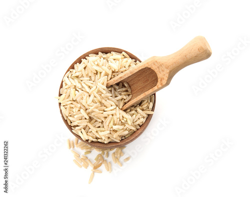 Bowl and scoop with raw unpolished rice on white background, top view