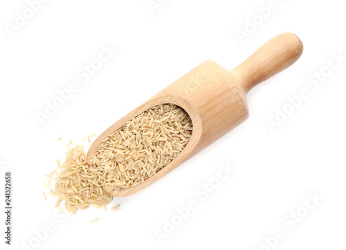 Wooden scoop with brown rice on white background, top view