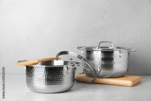 New clean saucepans on table against grey background, space for text