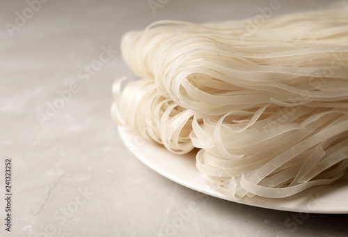 Plate with raw rice noodles on table, closeup. Space for text