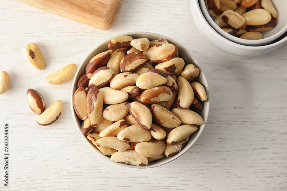 Bowls with tasty Brazil nuts on white wooden table, top view Bowls with tasty Brazil nuts on white wooden table, top view
