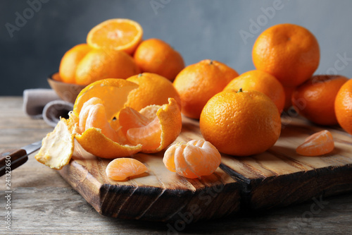Board with ripe tangerines on wooden table