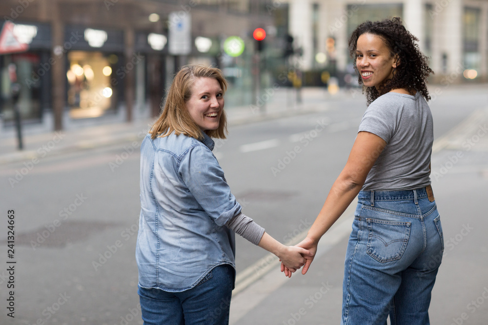 A lesbian couple holding hands looking back