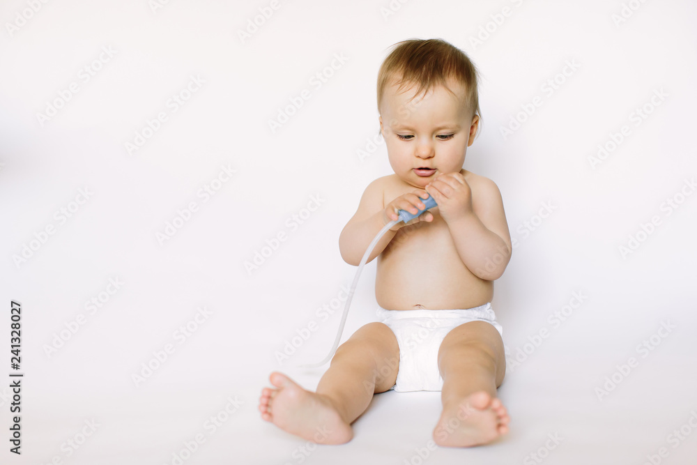 A baby girl holds a nasal aspirator on a white background A baby girl holds a nasal aspirator on a white background