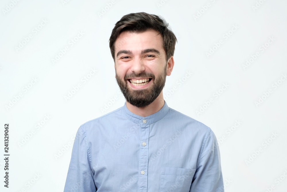 Hispanic man wearing blue shirt laughing or grinning having cheerful look. Hispanic man wearing blue shirt laughing or grinning having cheerful look.