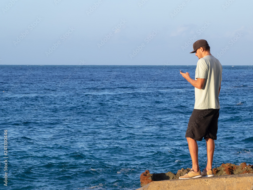 man with a smartphone. ocean background. summertime.