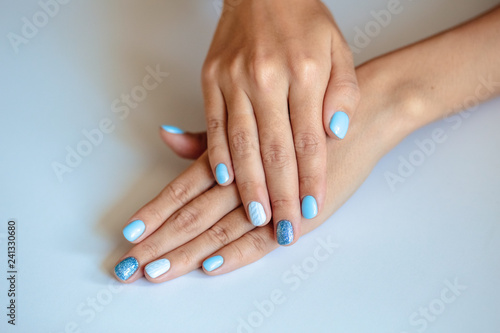 Gorgeous manicure, pastel tender blue color nail polish, closeup photo. Female hands over simple background