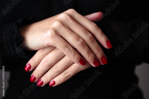 Gorgeous manicure  clssic red color nail polish  closeup photo. Female hands over dark fur background