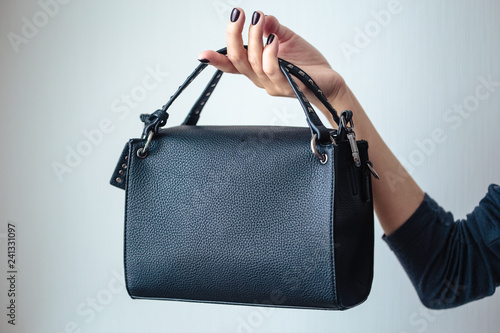 young woman with black small handbag with perfect dark violet manicure