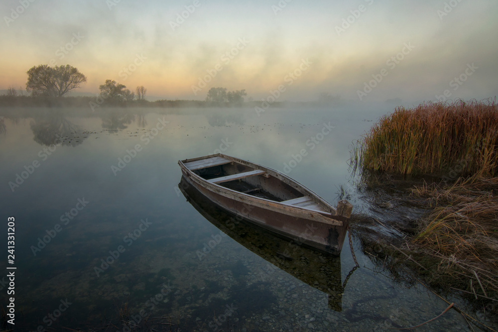 Boat on the river bank on a foggy morning