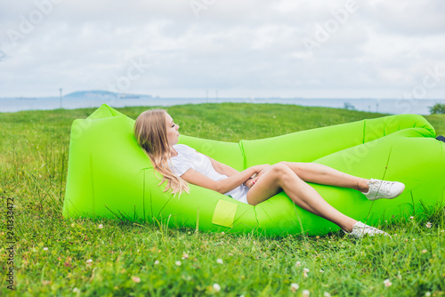 Young woman resting on an air sofa in the park. photo