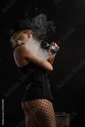 Young sexy woman is vaping. Studio shoot. E-cigarette. Smoke. 