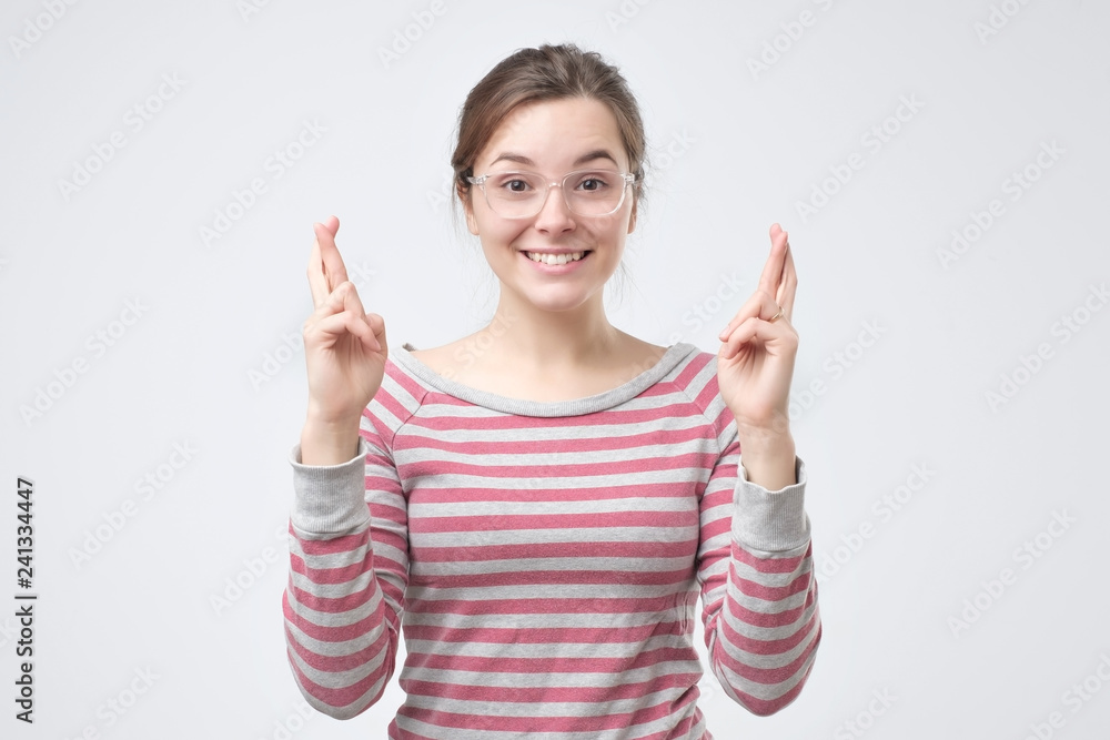 Girl having excited, superstitious and naive look, keeping fingers crossed Girl having excited, superstitious and naive look, keeping fingers crossed