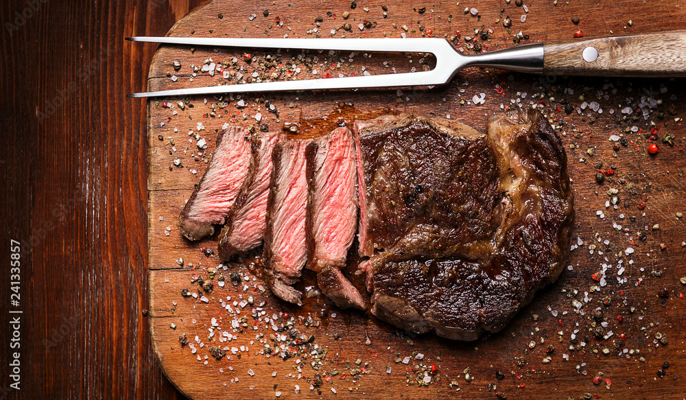 tasty and fresh, very juicy ribbey steak of marbled beef, on a wooden table.