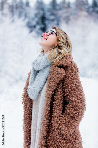 Beautiful girl in coat in a snow forest. Christmas of Valentine Day season time