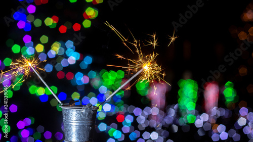 burning sparkler on bokeh background from lights of garland