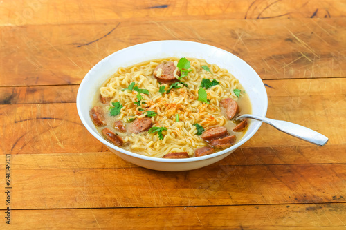 Bowl of Ramen Noodles with Sausage centered on Rustic Wooden Table