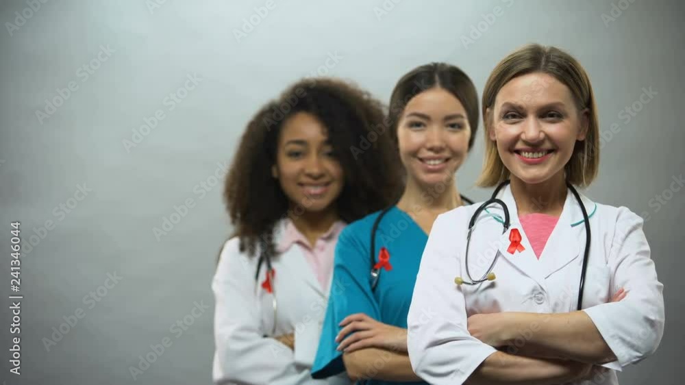 Smiling multiracial doctors with red ribbons, international AIDS awareness sign Smiling multiracial doctors with red ribbons, international AIDS awareness sign