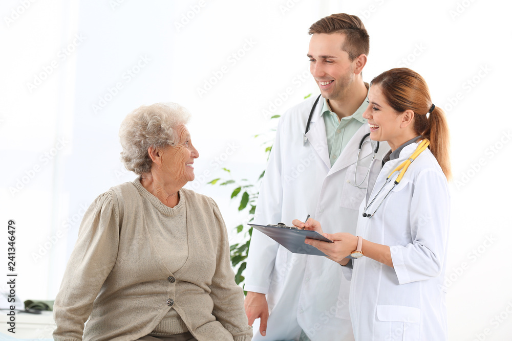 Doctor and medical assistant working with elderly patient in hospital Doctor and medical assistant working with elderly patient in hospital