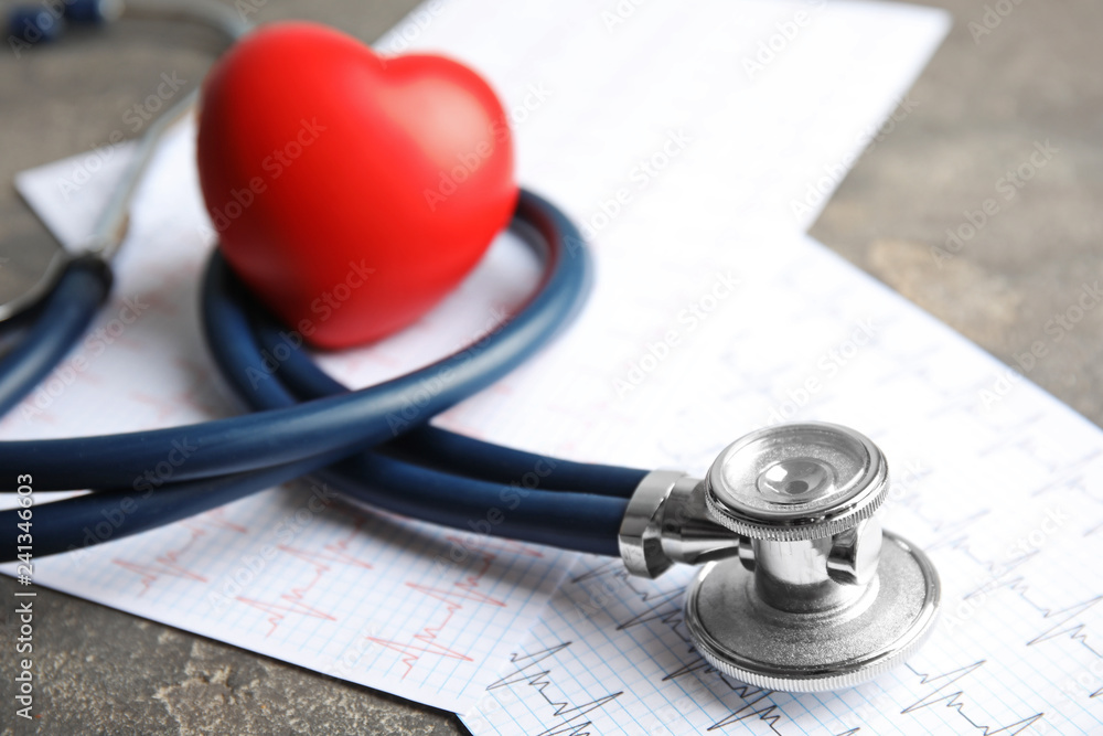 Stethoscope, red heart and cardiogram on gray table. Cardiology concept - obrazy, fototapety, plakaty 
