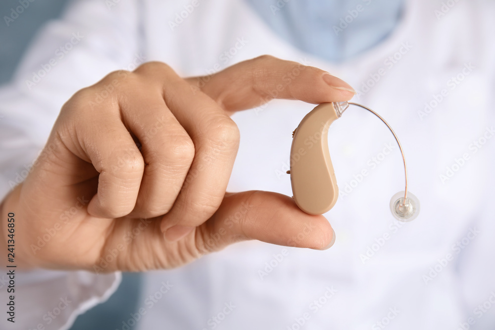 Doctor holding hearing aid, closeup. Medical device Doctor holding hearing aid, closeup. Medical device