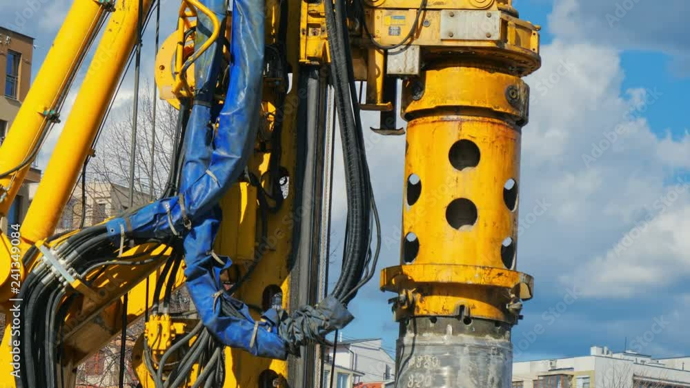 Heavy big excavator break trough holes for concrete colones for new road in construction site. Building a new streets in urban area, city town Heavy big excavator break trough holes for concrete colones for new road in construction site. Building a new streets in urban area, city town