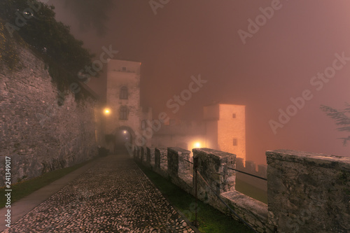 Walls and of ancient castle immersed in the mist during a winter night, Cison di Valmarino, Italy © Gianluca