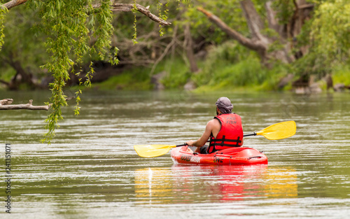 Un hombre remando en un kayak por el río disfrutando del paisaje