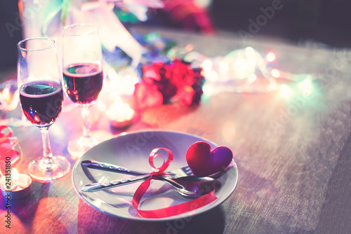 Valentines dinner romantic love concept Romantic table setting decorated with Red heart fork spoon on plate and couple champagne glass roses