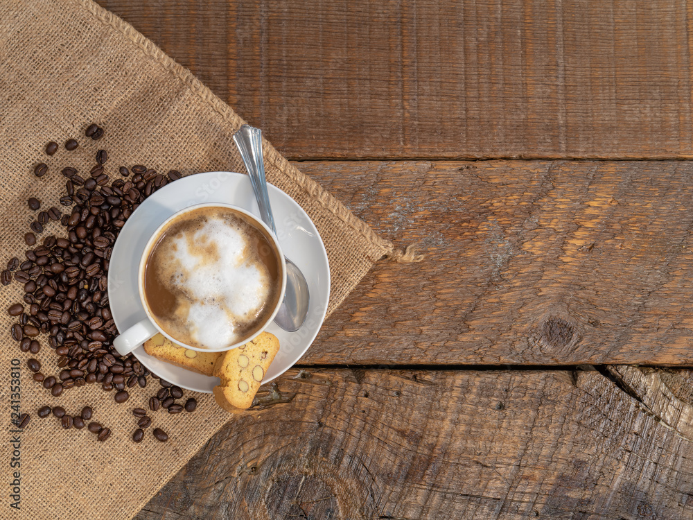 cup of coffee on wooden table with a biscotti on the side. cup of coffee on wooden table with a biscotti on the side.