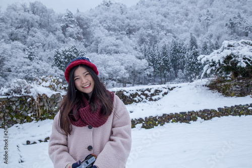Happy Girl in Shirakawa-go village area on winter during snowing, with traditional House Gassho style and one of UNESCO world heritage sites, Gifu, Japan