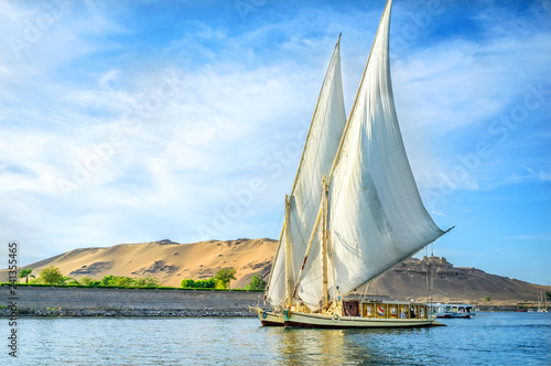 A traditional boat sailing through the Nile River in a late afternoon in Egypt